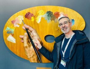 Christophe Baudin posant devant une palette transformée en œuvre d’art exposée au Grand Palais
